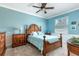 Comfortable bedroom featuring a wicker bed, complemented by a dresser and neutral carpeting at 5799 Linen Bluff Pl, Leesburg, FL 34748