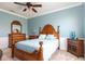Comfortable bedroom featuring a wicker bed, complemented by a dresser and neutral carpeting at 5799 Linen Bluff Pl, Leesburg, FL 34748