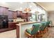 A kitchen with granite countertops, dark cabinets and backsplash, plus three barstools under the breakfast bar at 5799 Linen Bluff Pl, Leesburg, FL 34748