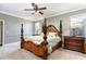 Main bedroom with carpet, an ornate bed frame, decorative ceiling fan, and luxurious furnishings at 5799 Linen Bluff Pl, Leesburg, FL 34748