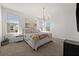 Serene main bedroom with a decorative chandelier, plush bedding, and natural light from two windows at 7409 Inlet Pt, Celebration, FL 34747