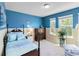 Charming bedroom with blue accent wall, dresser, and two windows for natural light at 7545 Azalea Cove Cir, Orlando, FL 32807