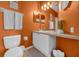 Bathroom featuring single vanity, large mirror, and orange painted walls at 8160 Sun Palm Dr, Kissimmee, FL 34747