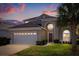 Sunset view of a charming two-story home featuring a well-manicured lawn and a two-car garage at 8160 Sun Palm Dr, Kissimmee, FL 34747