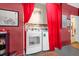 Bright laundry room with modern washer and dryer behind bright red curtains with a humorous white board on the wall at 8160 Sun Palm Dr, Kissimmee, FL 34747