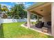 Well-manicured backyard featuring green lawn, privacy fence, and covered patio with relaxing lounge furniture at 9963 Hartford Maroon Rd, Orlando, FL 32827