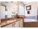 Bathroom featuring a granite vanity top, soaking tub, and soft natural light at 9963 Hartford Maroon Rd, Orlando, FL 32827