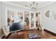 View of a home office with a desk and chair, glass french doors, hardwood floors, and modern decor at 10626 Bonne Chance Dr, Orlando, FL 32832