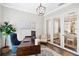 Elegant home office featuring hardwood floors, a modern chandelier, glass french doors, and neutral decor at 10626 Bonne Chance Dr, Orlando, FL 32832