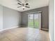 Bright bedroom featuring neutral walls, tile floors, and a sliding glass door to the backyard at 107 Carlisle Ct, Kissimmee, FL 34758