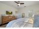 Bright bedroom featuring a ceiling fan, TV, wooden dresser, and a comfortable bed, creating a relaxing atmosphere at 112 Southern Pecan Cir # 201, Winter Garden, FL 34787