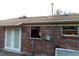 Back exterior view highlighting brick wall, french doors, broken windows and brown roof at 135 Bob Thomas Cir, Sanford, FL 32771