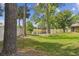 Serene backyard view with mature trees, lush green lawn, and a partial view of the lake at 194 Heron Bay Cir, Lake Mary, FL 32746
