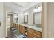 Bathroom featuring double sinks, wooden cabinets, a large mirror, a skylight, and access to the shower at 194 Heron Bay Cir, Lake Mary, FL 32746
