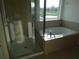 Bathroom featuring a glass-door shower and soaking tub under a window at 2737 Monticello Way, Kissimmee, FL 34741