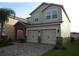 Two-story home with a brick driveway, two-car garage, stone details, and muted green paint at 2737 Monticello Way, Kissimmee, FL 34741