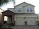 Two-story home with a brick driveway, two-car garage, stone details, and muted green paint at 2737 Monticello Way, Kissimmee, FL 34741