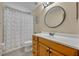 Bathroom with wood cabinets, updated shower, decorative round mirror, and toilet at 2810 Windsong Ln, St Cloud, FL 34772