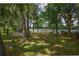 Landscaped backyard with mature trees, a basketball court, picnic tables, and lake access with a dock at 3306 Fishermans Cv, Winter Park, FL 32792