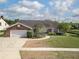Charming brick home featuring a lush front yard, mature trees, and attached two-car garage at 3306 Fishermans Cv, Winter Park, FL 32792