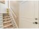 Carpeted stairway with white risers ascends to the next level with a paneled wall and white door at 35 Misners Trl, Ormond Beach, FL 32174