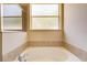 Cozy bathroom with a large soaking tub beneath a bright window, and neutral-toned tiles at 3812 Creswick Cir, Orlando, FL 32829