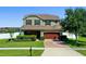 Charming two-story home featuring manicured landscaping, a brick driveway, and a two-car garage at 4113 Longbow Dr, Clermont, FL 34711