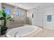 The main bathroom features a large soaking tub, and a glass-enclosed shower, plus neutral tile flooring at 4113 Longbow Dr, Clermont, FL 34711