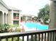 An elevated view of the blue community pool surrounded by lush landscaping and beige buildings at 455 Wymore Rd # 203, Altamonte Springs, FL 32714