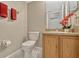 Bathroom showing a toilet, vanity with wooden cabinets, and a marble-like floor, offering a clean and organized space at 4574 Ficus Tree Rd, Kissimmee, FL 34758