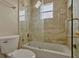 Bathroom featuring marble tiling, a shower-tub combo, and a glass door, offering a modern and functional design at 4574 Ficus Tree Rd, Kissimmee, FL 34758