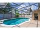 A screened-in pool area with a freeform pool, hot tub, and outdoor living space in a fenced yard at 4574 Ficus Tree Rd, Kissimmee, FL 34758