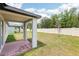 A covered patio with brick flooring and a spacious backyard with a white vinyl fence at 4717 Jasmine Cir, Leesburg, FL 34748