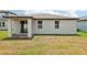 Back exterior showcasing a covered patio with brick flooring, and a spacious grassy yard at 4717 Jasmine Cir, Leesburg, FL 34748