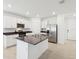 Modern kitchen features white cabinets, stainless steel appliances, a center island, and tile flooring at 4717 Jasmine Cir, Leesburg, FL 34748