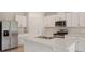 Bright kitchen features white cabinets, stainless steel appliances, a large island and quartz countertops at 4728 Jasmine Cir, Leesburg, FL 34748