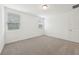 Cozy bedroom with neutral carpet, two bright windows, and a door for easy access at 4732 Jasmine Cir, Leesburg, FL 34748