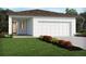 New construction home with an attached garage, a well-manicured lawn and colorful front yard landscaping at 4981 Kaia Ave, Winter Haven, FL 33884