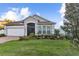 Charming single-story home featuring a manicured lawn and colorful flower beds under a blue sky at 600 Rob Roy Dr, Clermont, FL 34711