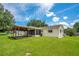 A serene backyard with a covered patio, lush green lawn, and a view of mature trees at 6426 Sw 60 Ave, Ocala, FL 34474