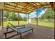 A covered deck has chairs that are facing a green lawn and a white shed at 6426 Sw 60 Ave, Ocala, FL 34474