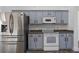 Bright kitchen with stainless steel refrigerator, white appliances, gray cabinets, and herringbone flooring at 655 Eagle Pointe South, Kissimmee, FL 34746