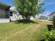 This property features a spacious backyard, showcasing mature trees and a well-kept lawn, adjacent to a screened patio at 741 Truman Ave, Lady Lake, FL 32159