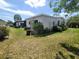 Exterior home view with lush landscaping, a screened patio, and ample yard space at 741 Truman Ave, Lady Lake, FL 32159