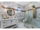 Lavish bathroom with marble walls, glass shower, and a round mirror above the vanity at 8625 Brixford St, Orlando, FL 32836
