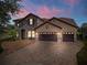 Elegant two-story home with stone accents, tile roof, and a three-car garage at dusk at 8625 Brixford St, Orlando, FL 32836