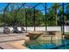A jacuzzi flows into a stunning pool, surrounded by lounge chairs within a screened in enclosure at 8625 Brixford St, Orlando, FL 32836