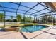 A screened-in pool with a jacuzzi, travertine tile pool deck and well-manicured landscaping enhance this backyard at 8625 Brixford St, Orlando, FL 32836