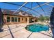A spacious travertine tile pool deck features a pristine pool, flowing jacuzzi and covered outdoor cooking space at 8625 Brixford St, Orlando, FL 32836