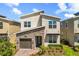 Modern two-story home featuring a stone facade, manicured lawn, and a one-car garage at 9179 Sommerset Hills Dr, Davenport, FL 33896